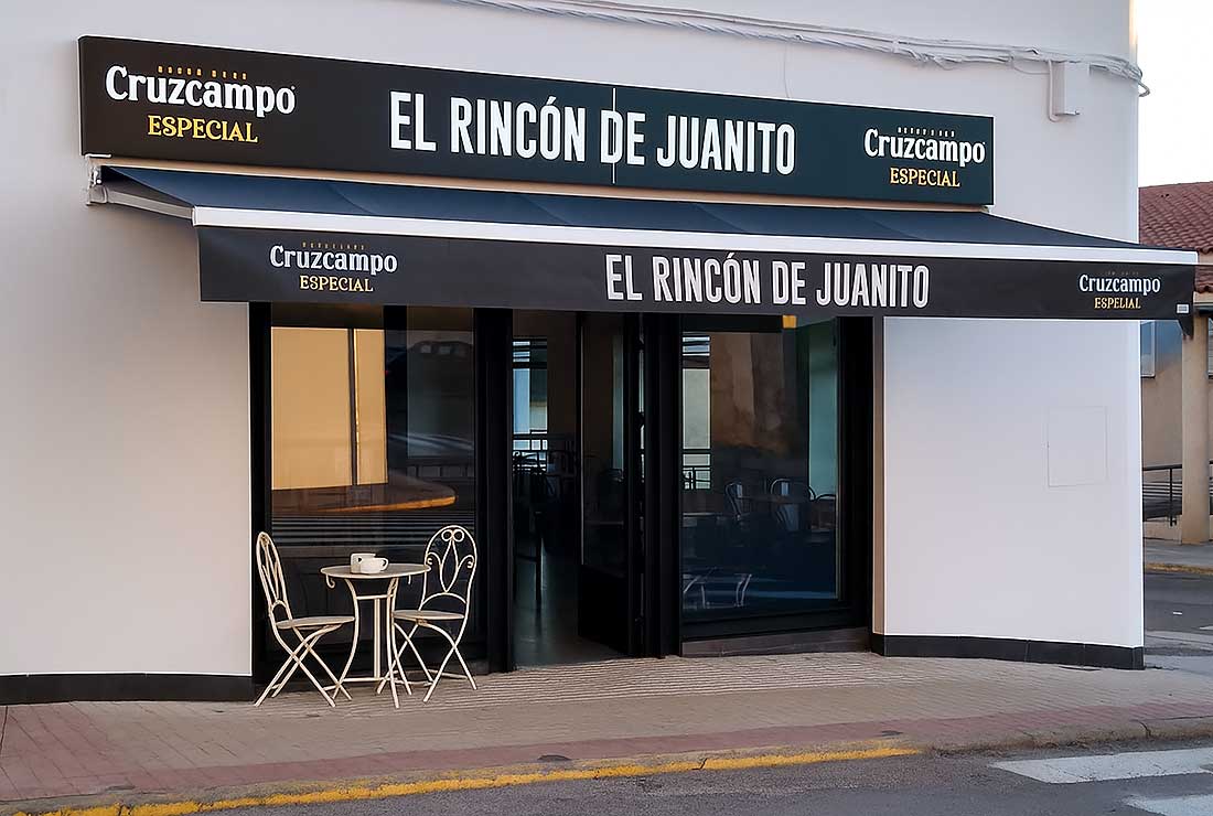 Fachada de un restaurante llamado "El Rincón de Juanito" con toldo negro.